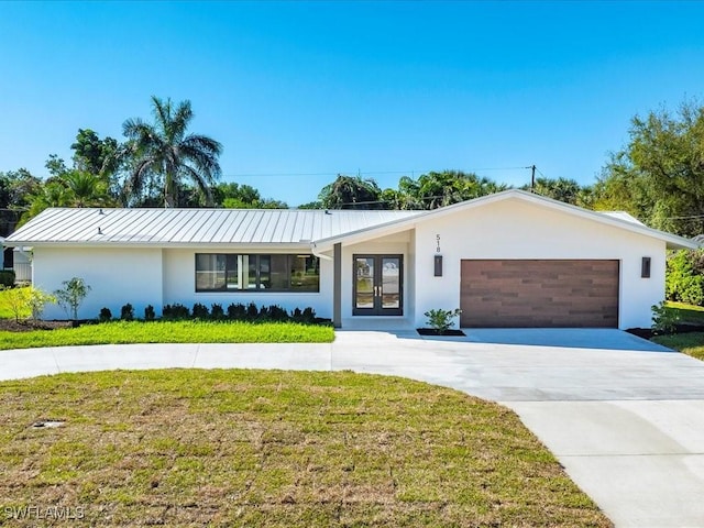 single story home with a front yard, a garage, metal roof, stucco siding, and french doors