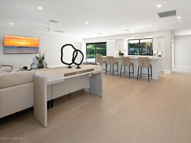 living room featuring visible vents, light wood-type flooring, and recessed lighting