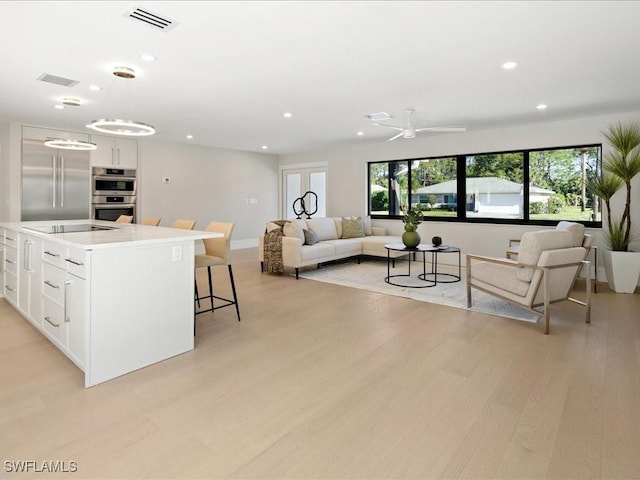 living area with visible vents, recessed lighting, and light wood-style flooring