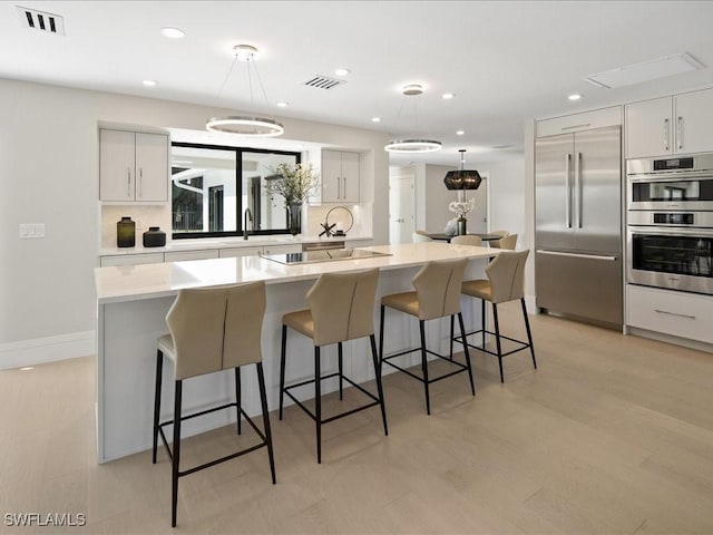 kitchen featuring decorative light fixtures, visible vents, stainless steel appliances, and a kitchen island