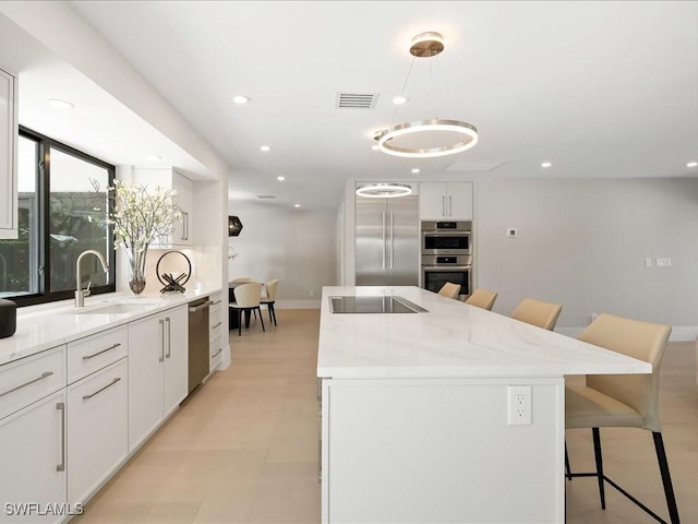 kitchen featuring recessed lighting, a kitchen island with sink, stainless steel appliances, a sink, and visible vents