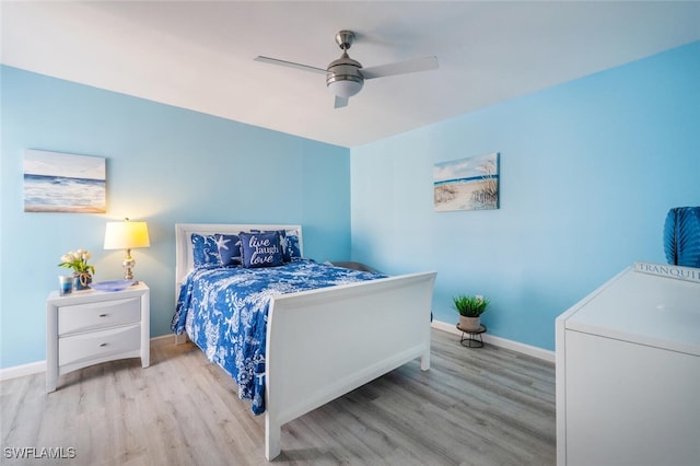 bedroom with a ceiling fan, washer / dryer, wood finished floors, and baseboards