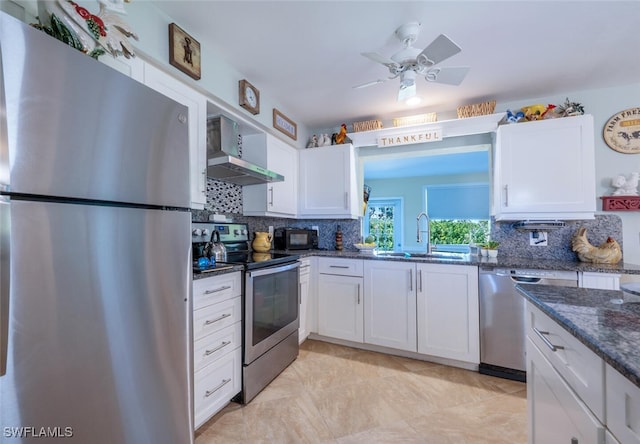 kitchen with a sink, white cabinetry, appliances with stainless steel finishes, wall chimney range hood, and decorative backsplash
