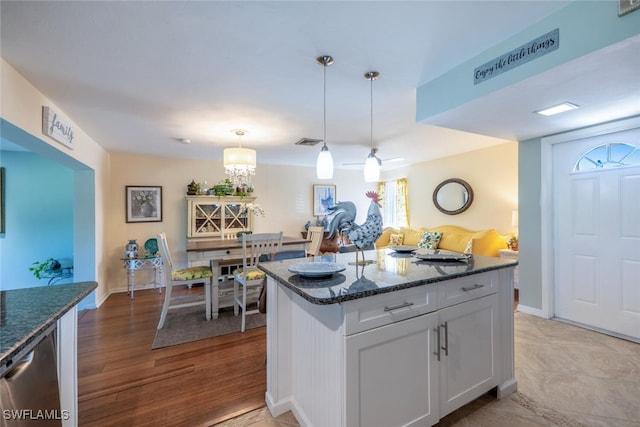 kitchen with dark stone countertops, visible vents, white cabinets, light wood-style floors, and pendant lighting