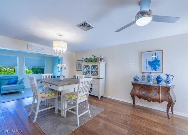 dining area with visible vents, baseboards, wood finished floors, and ceiling fan with notable chandelier