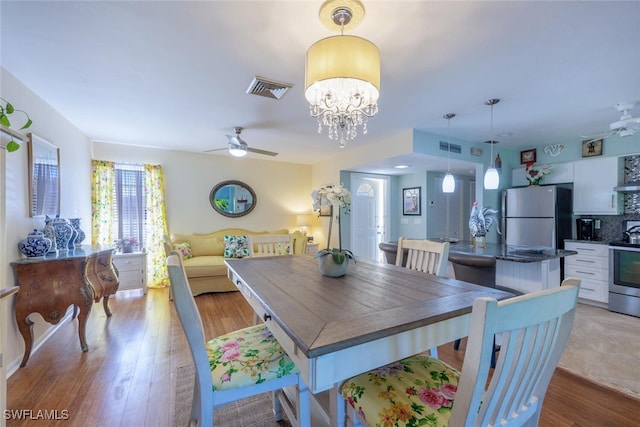 dining room featuring visible vents, ceiling fan with notable chandelier, and light wood-style floors