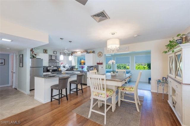dining room featuring a chandelier, visible vents, baseboards, and light wood-style floors