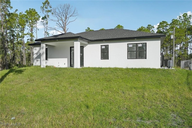 rear view of house featuring stucco siding and a yard