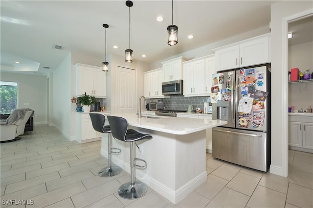 kitchen with decorative backsplash, white cabinets, appliances with stainless steel finishes, and light countertops