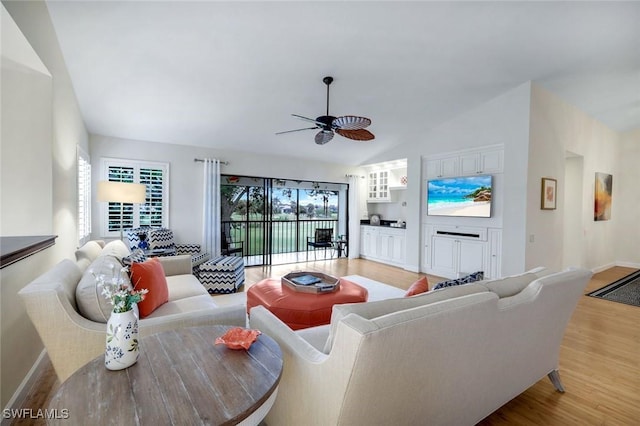 living room with a wealth of natural light, light wood-style flooring, vaulted ceiling, and ceiling fan