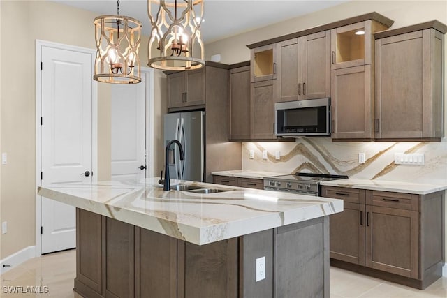 7282 Saona Ct, Naples, FL 34113 - kitchen featuring stainless steel appliances, a sink, light stone countertops, an island with sink, and backsplash
