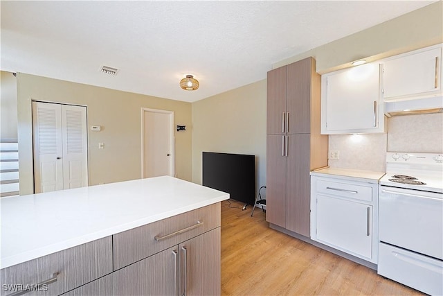 kitchen featuring light wood-type flooring, light countertops, white cabinetry, and white range with electric cooktop