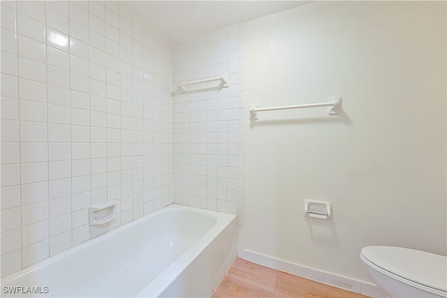 bathroom featuring baseboards, bathtub / shower combination, toilet, and wood finished floors