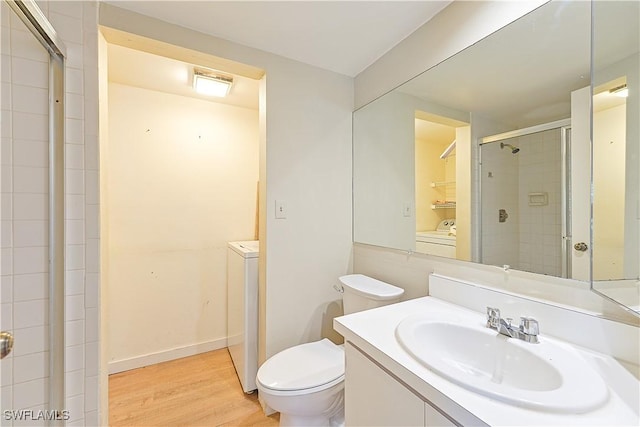 full bath with washing machine and clothes dryer, wood finished floors, a stall shower, and toilet