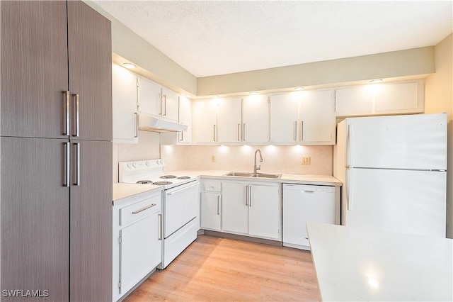 kitchen featuring light countertops, white appliances, under cabinet range hood, a sink, and light wood-type flooring