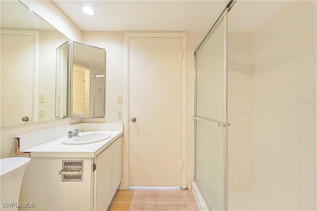 bathroom with a stall shower, wood finished floors, and vanity