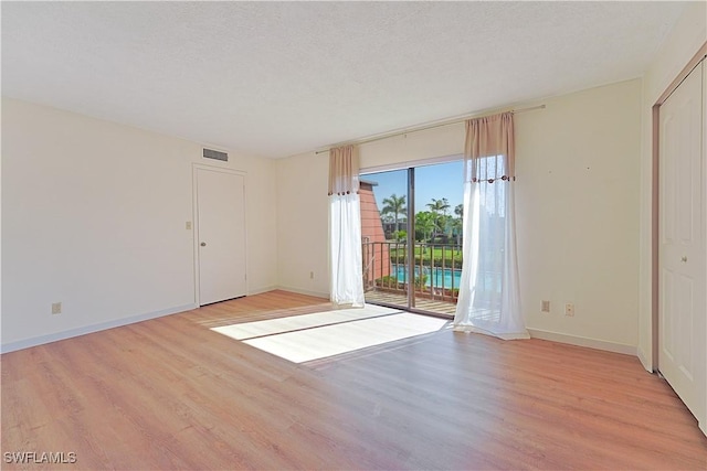 empty room with visible vents, light wood-style flooring, and a textured ceiling