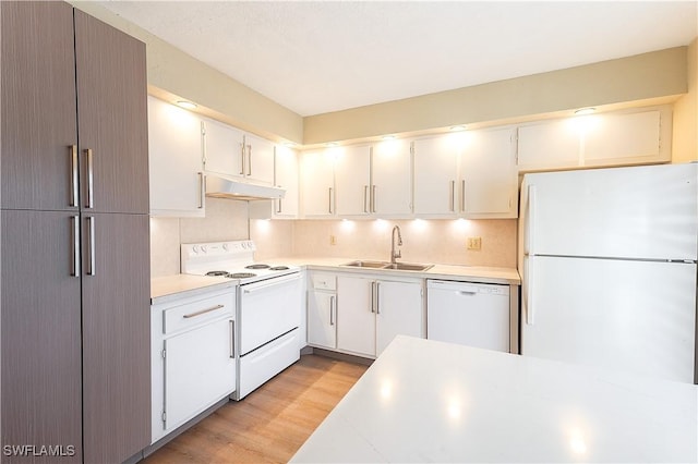 kitchen with light countertops, white appliances, under cabinet range hood, a sink, and light wood-style floors
