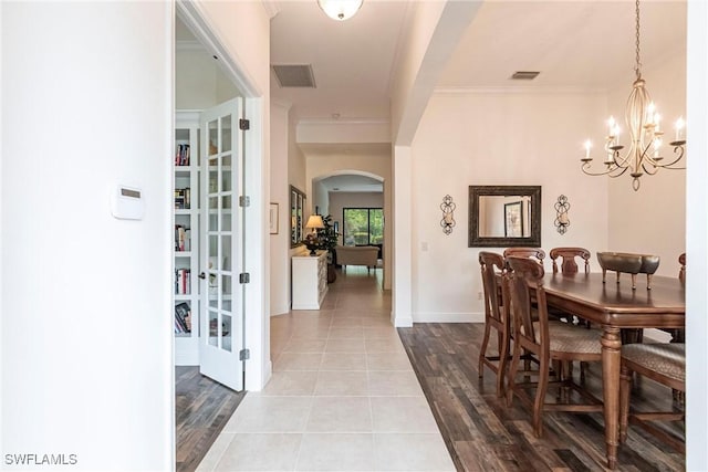 dining area with wood finished floors, arched walkways, a notable chandelier, and visible vents