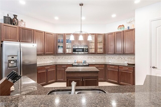 kitchen featuring pendant lighting, a sink, backsplash, and appliances with stainless steel finishes