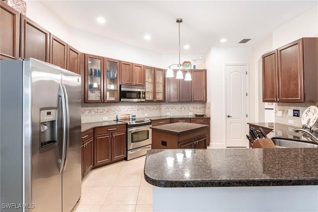 kitchen with light tile patterned flooring, a sink, a peninsula, stainless steel appliances, and visible vents