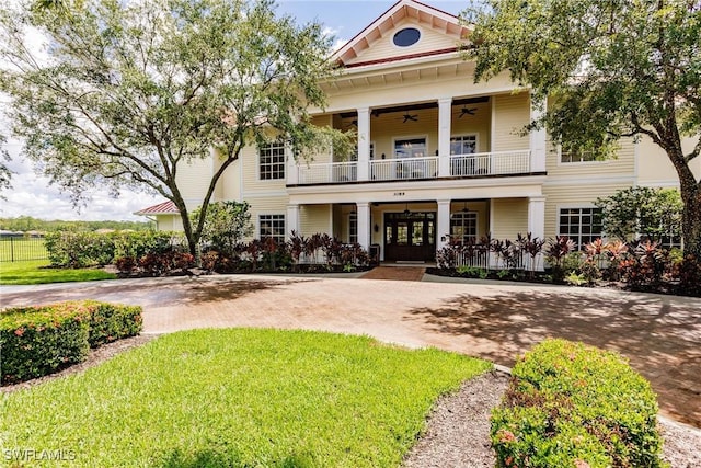 neoclassical home with french doors, curved driveway, a ceiling fan, a balcony, and a front lawn