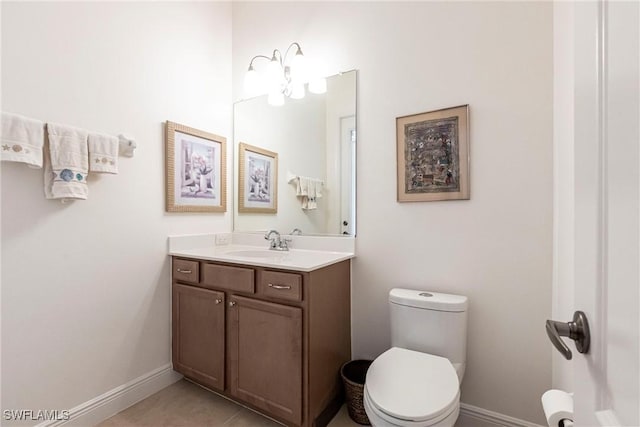 half bathroom with baseboards, toilet, tile patterned flooring, and vanity
