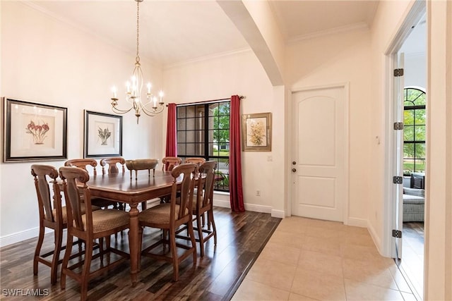 dining space with arched walkways, ornamental molding, baseboards, and an inviting chandelier