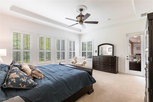 carpeted bedroom featuring baseboards, a tray ceiling, visible vents, and a ceiling fan