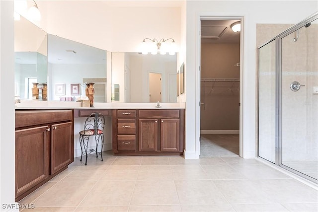 bathroom with a shower stall, a walk in closet, tile patterned flooring, and vanity
