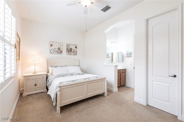 bedroom with arched walkways, baseboards, visible vents, and light colored carpet