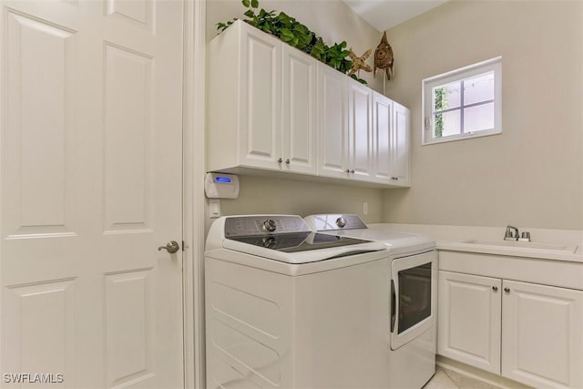 clothes washing area featuring washing machine and dryer, cabinet space, and a sink