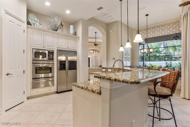 kitchen featuring stone counters, pendant lighting, a kitchen breakfast bar, a warming drawer, and stainless steel appliances