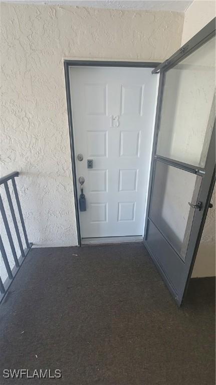 exterior space featuring dark colored carpet and a textured wall