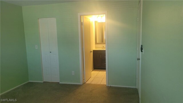 unfurnished bedroom featuring light carpet, a closet, and baseboards