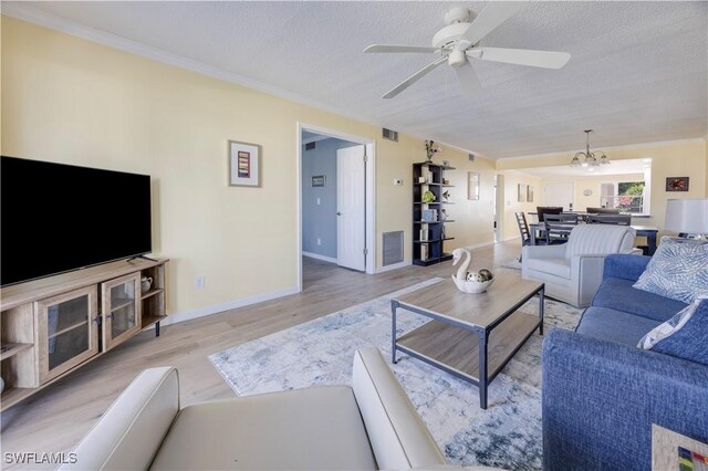2445 W Gulf Dr Unit 21E, Sanibel, FL 33957 - living room featuring ceiling fan with notable chandelier, a textured ceiling, crown molding, and wood finished floors