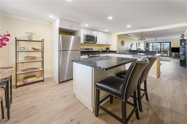 2445 W Gulf Dr Unit 21E, Sanibel, FL 33957 - kitchen featuring a kitchen bar, appliances with stainless steel finishes, a peninsula, and light wood finished floors
