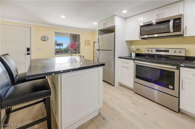 2445 W Gulf Dr Unit 21E, Sanibel, FL 33957 - kitchen with stainless steel appliances, a kitchen breakfast bar, white cabinets, and light wood-style flooring