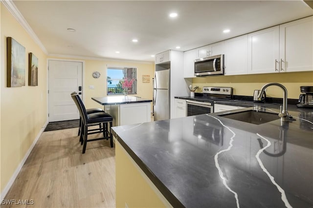 2445 W Gulf Dr Unit 21E, Sanibel, FL 33957 - kitchen with dark countertops, ornamental molding, appliances with stainless steel finishes, white cabinetry, and a sink