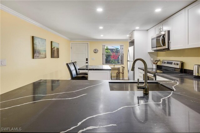 2445 W Gulf Dr Unit 21E, Sanibel, FL 33957 - kitchen with white cabinetry, stainless steel countertops, appliances with stainless steel finishes, and a center island