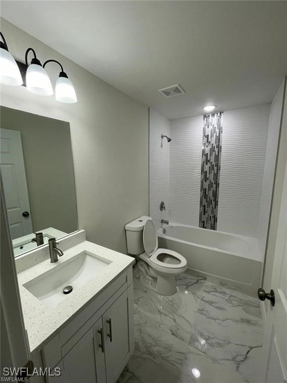 4748/4750 30th St SW, Lehigh Acres, FL 33973 - bathroom featuring vanity, marble look tiles, toilet, and washtub / shower combination