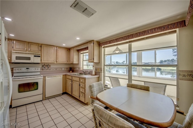 kitchen with light countertops, visible vents, white appliances, a sink, and light brown cabinetry