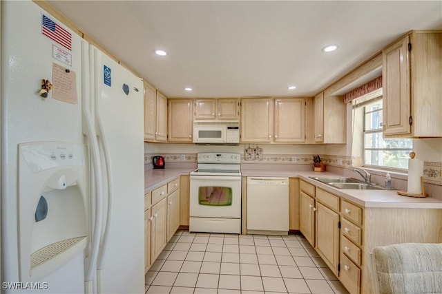 kitchen with white appliances, light brown cabinetry, light countertops, and a sink