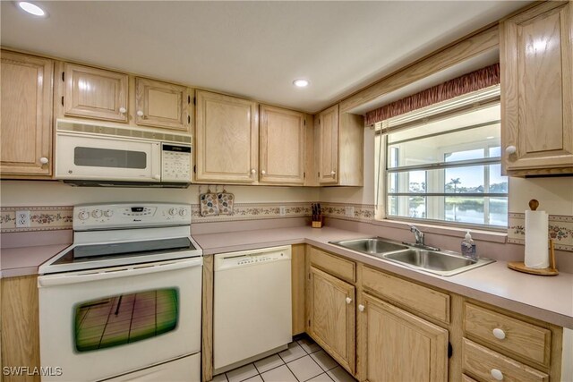 kitchen with white appliances, light brown cabinetry, light countertops, and a sink