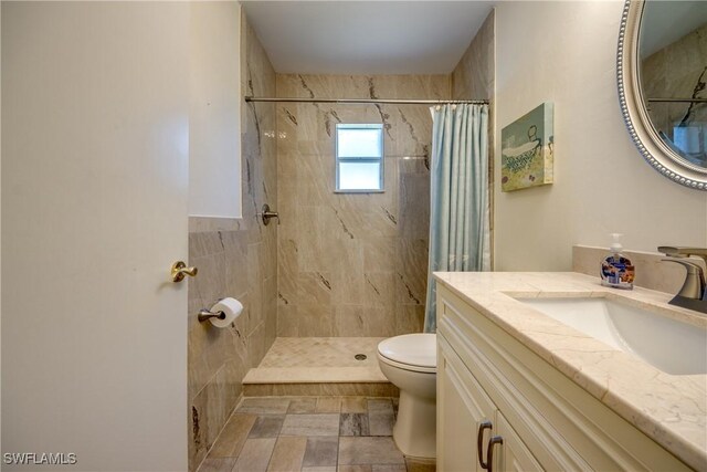 full bathroom featuring vanity, toilet, and tiled shower