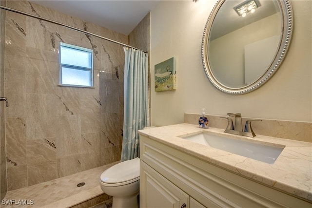 bathroom featuring a tile shower, toilet, and vanity