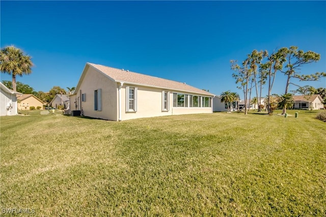 rear view of house featuring stucco siding and a lawn