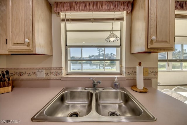 kitchen with light countertops, a sink, and light brown cabinetry