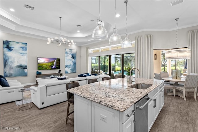 kitchen with a sink, a chandelier, open floor plan, ornamental molding, and white cabinets