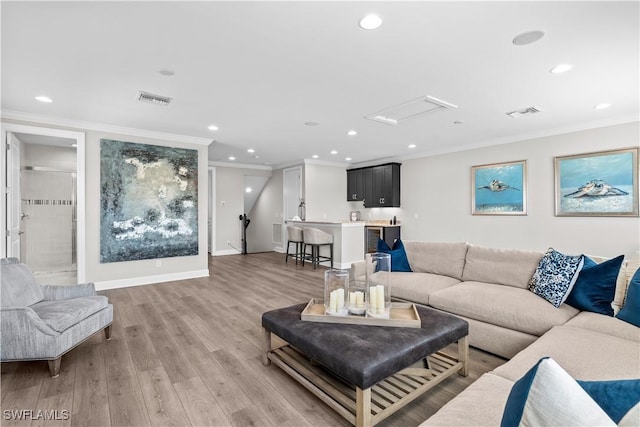 living room with crown molding, recessed lighting, light wood-type flooring, and baseboards